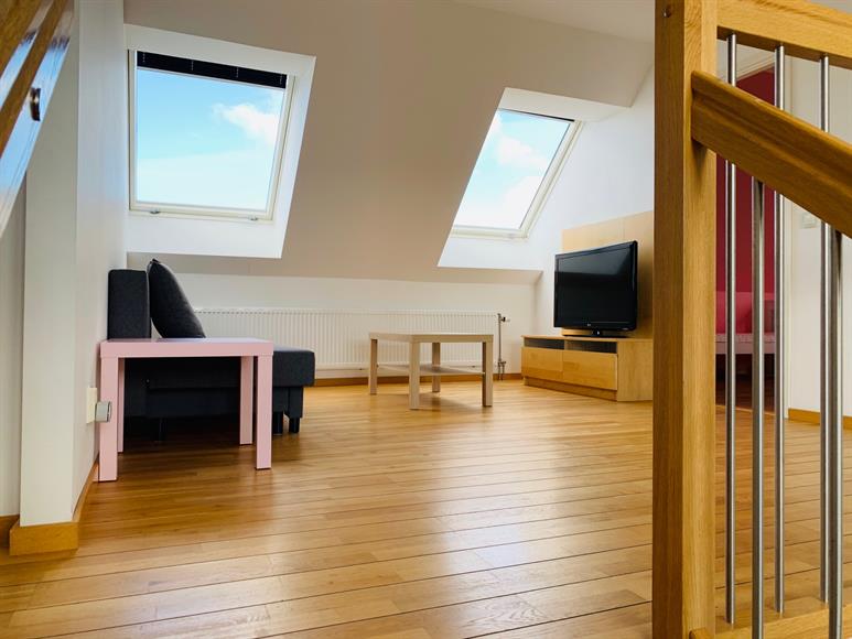 Uppför trappan till plan 2 ligger ytterligare ett luftigt vardagsrum/öppet TV rum för spel och lek. Bäddsoffan här möjliggör extra gästutrymme.
Up the stairs to the 2nd floor is another spacious living room / open TV room for games and play. The sofa bed here allows for extra guest space.