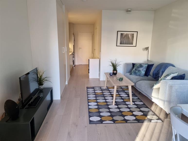 Vardagsrum med soffa och tillhörande bord, TV med TV bänk samt garderobsutrymme