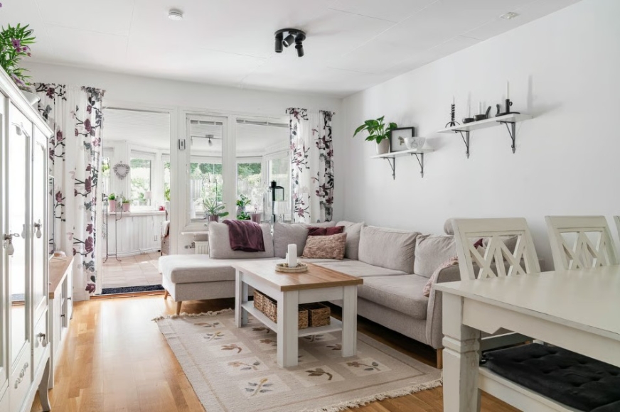 Vardagsrum i anslutning till uterummet. Soffhörna, soffbord, TV-möbel och matsalsbord och stolar.