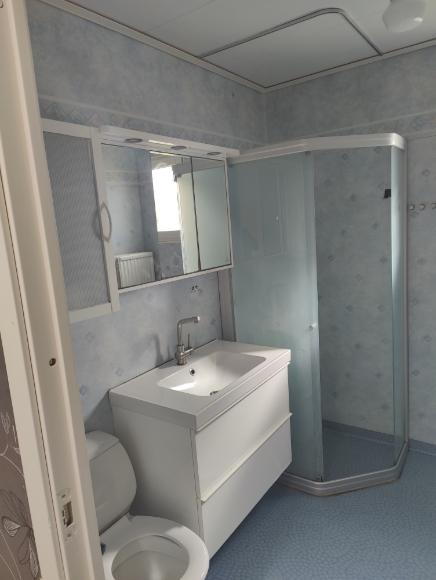 Ett badrum på övre plan med toalett, duschkabin, kommod, spegelskåp samt ett förvaringsskåp.