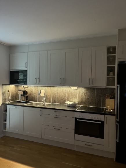 Bild mot kök. Kylskåp & frys, mikro, ugn och diskmaskin.