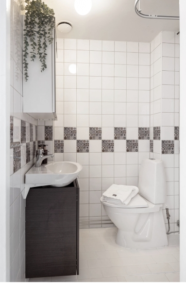 Badrum
Badrummet är stilrent helkaklat med vitt kakel på väggar och ljus klinker på golvet. Här finns toalett, handfat med underliggande skåp, spegelskåp och dusch.